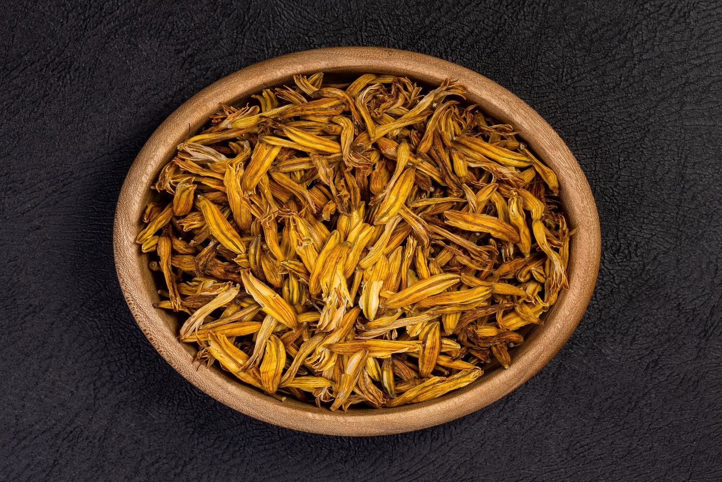 Dried yellow petals of aloe flower in a wooden bowl