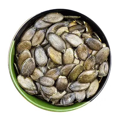 A close-up of a bowl containing dried  pumpkin seeds, highlighting their irregular shapes and golden-brown hue.