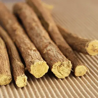 A pile of dried licorice root sticks arranged on a wooden table, showcasing their natural texture and color.