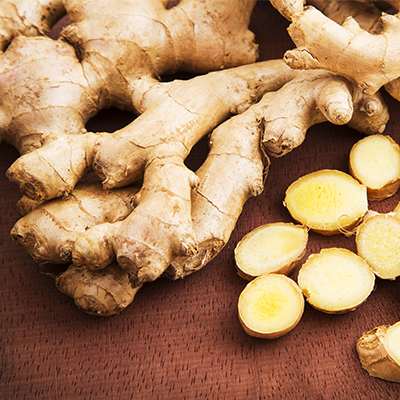 A close-up of a pile of fresh ginger root, showcasing its knobby texture and earthy brown skin.