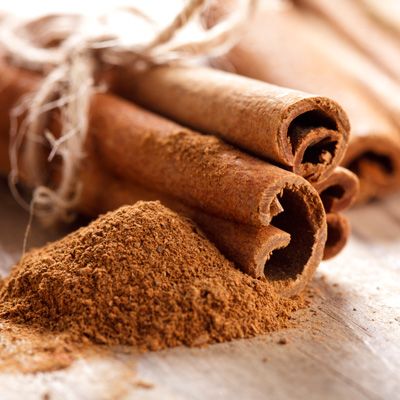 Close-up of cinnamon sticks and ground cinnamon on a textured wooden surface.