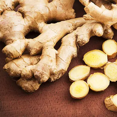 A close-up of a pile of fresh ginger root, showcasing its knobby texture and earthy brown skin.