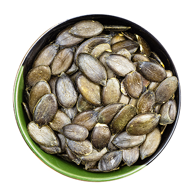 A close-up of a bowl containing dried  pumpkin seeds, highlighting their irregular shapes and golden-brown hue.
